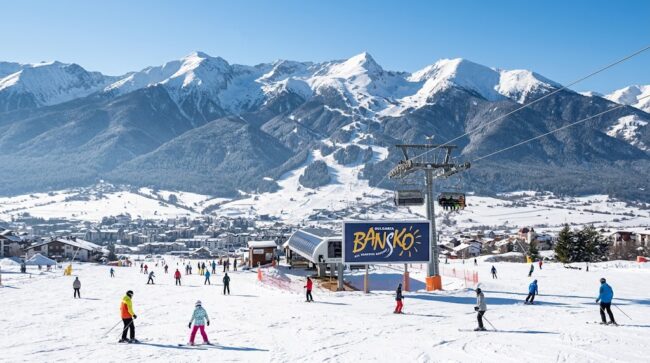 Overview of skiers on snow slopes and lift at Bansko ski resort